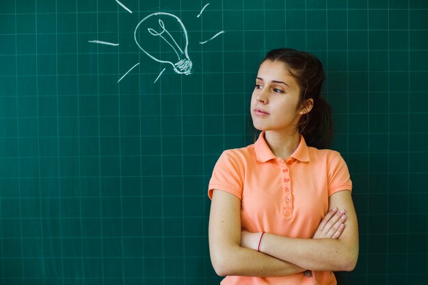 Serious student posing in front of the blackboard