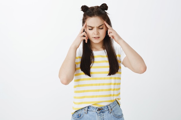 serious stylish young woman posing against white wall