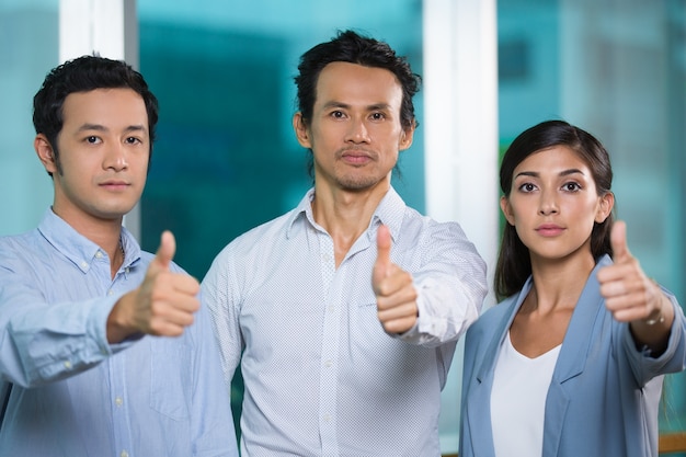 Serious successful business team showing thumbs-up