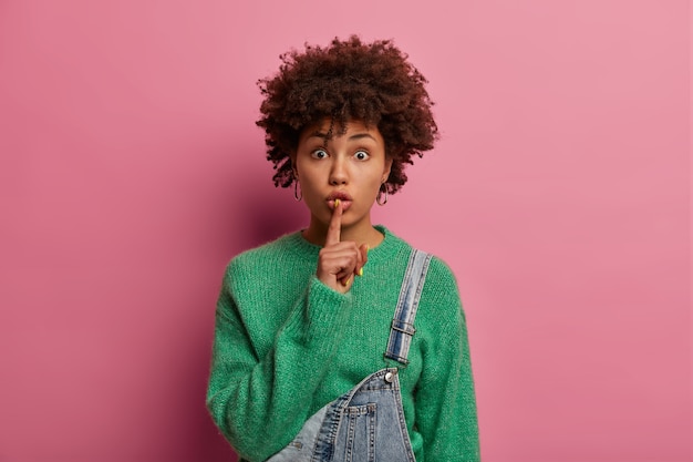 Serious surprised curly woman demands silence