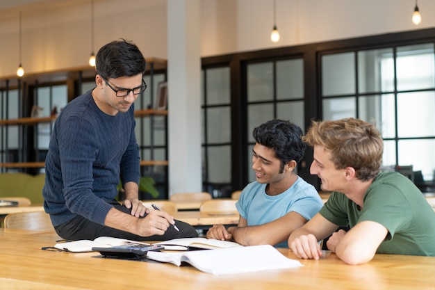 Serious teacher checking assignment of two students