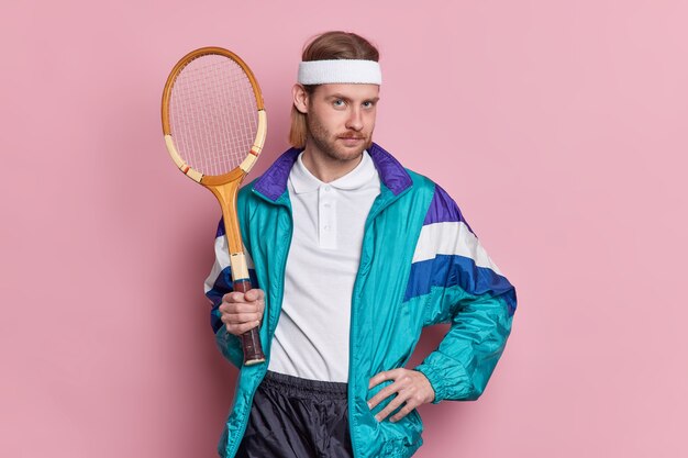 Serious tennis player with sport equipment keeps hand on waist looks confidently ready for game leads active lifestyle.