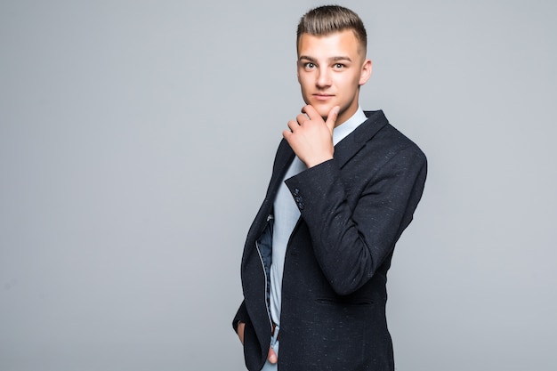 Serious thinking man in suite posing in front of light wall