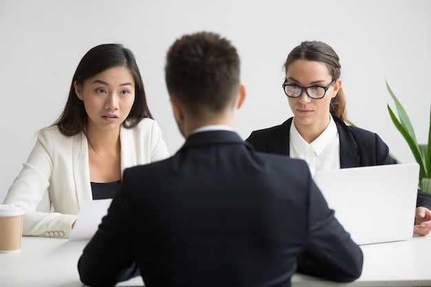 Serious unconvinced diverse hr managers interviewing male job applicant
