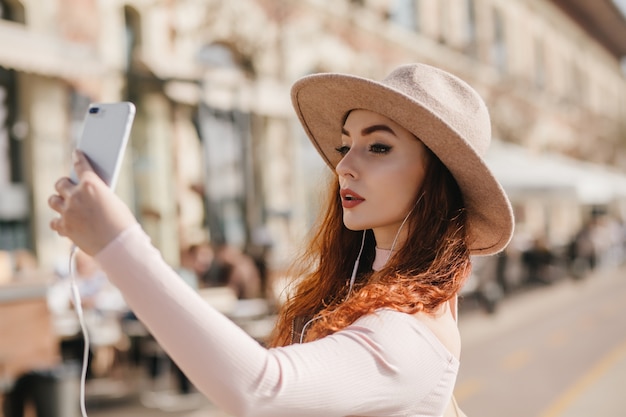 Serious white woman with dark makeup taking picture of herself