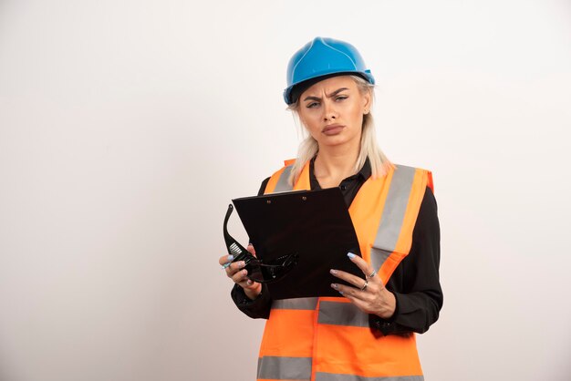 Serious woman builder with helmet holding clipboard . High quality photo