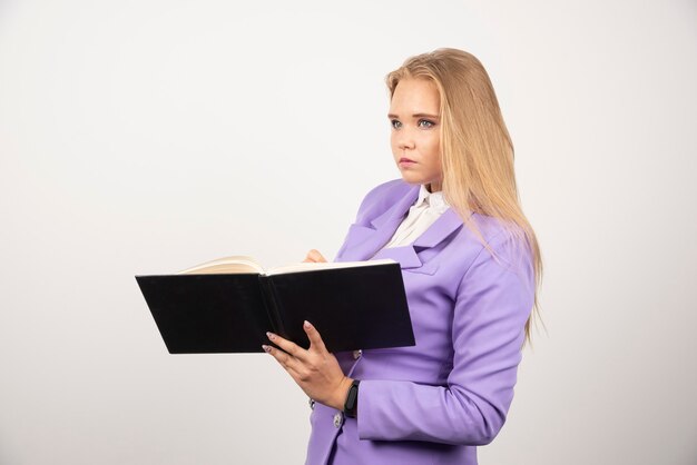 Serious woman holding opened tablet on white.