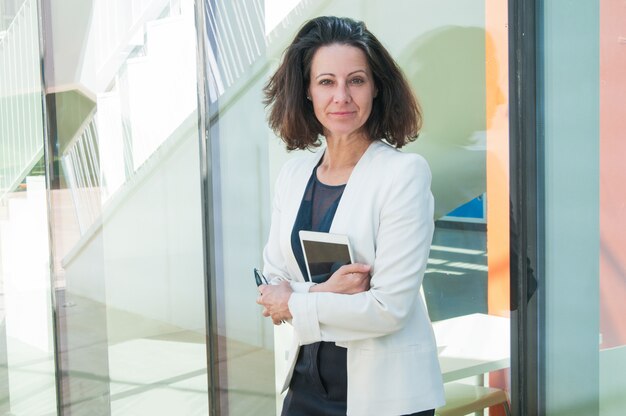 Serious woman holding phone and tablet in hands