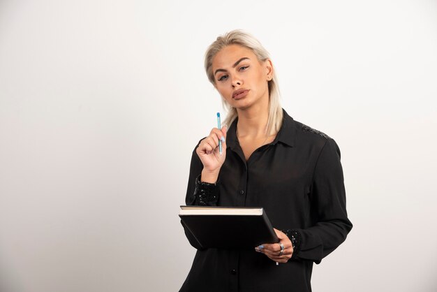 Serious woman posing with a pencil and clipboard on white background. High quality photo