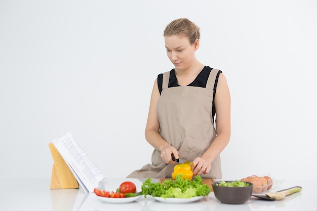 料理中のレシピ帳を読んでいる真剣な女性