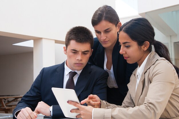 Serious woman showing tablet screen to business people