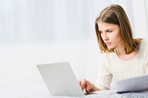 Serious woman with papers using laptop