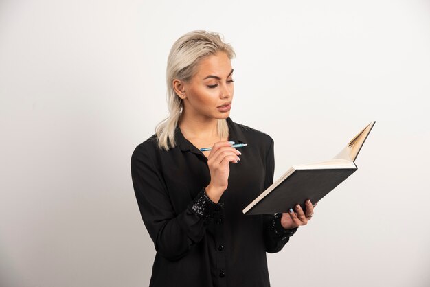 Free photo serious woman with pencil looking on clipboard on white background. high quality photo