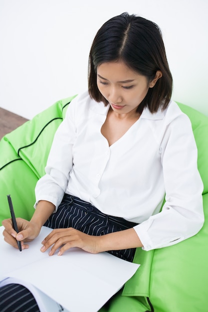 Serious Woman Writing and Sitting in Beanbag Chair