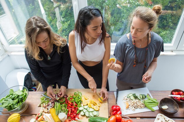 Серьезные женщины в чате и нарезка овощей на кухне