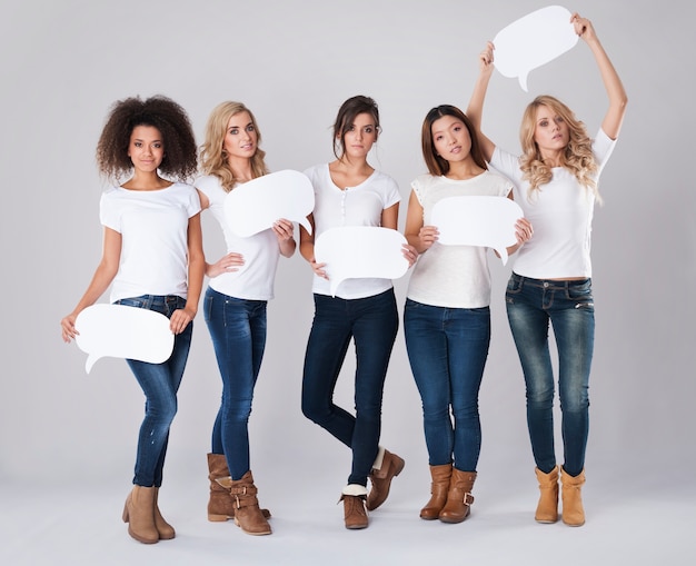 Serious women from different nationalities holding speech bubbles