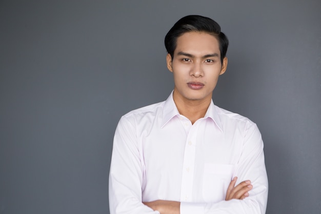 Free photo serious young asian businessman with crossed arms