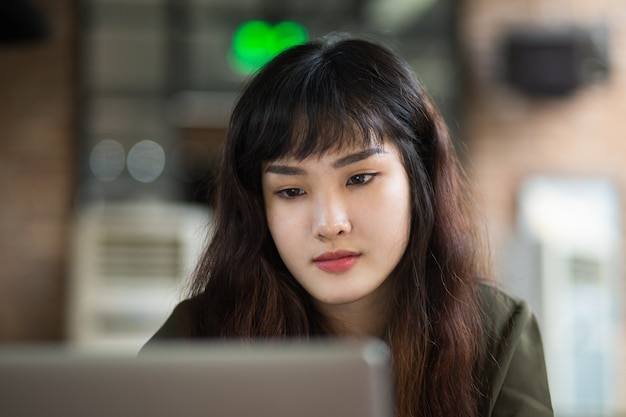 노트북에서 일하는 심각한 젊은 아시아 여자