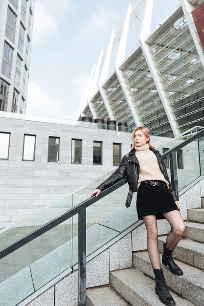 Serious young blonde lady outdoors holding cigarette.