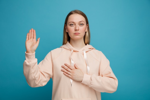 Serious young blonde woman doing promise gesture 