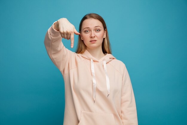 Serious young blonde woman pointing down 