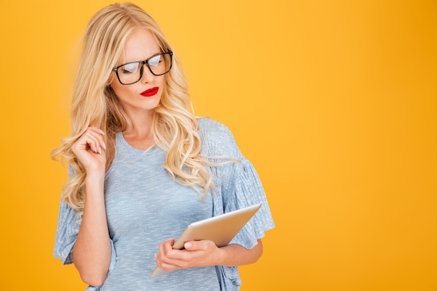 Serious young blonde woman using tablet computer.