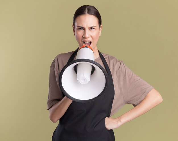 Serious young brunette barber girl in uniform speaks into loud speaker