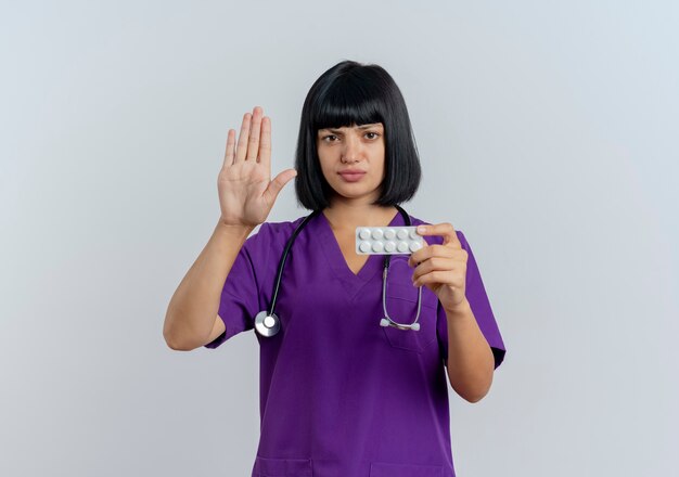 Serious young brunette female doctor in uniform with stethoscope