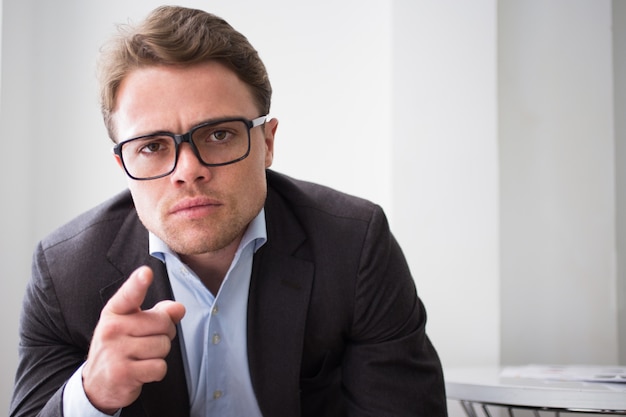 Serious young businessman pointing to camera