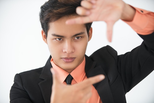 Serious young businessman showing finger frame