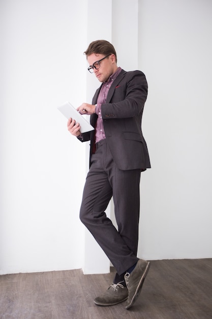 Serious young businessman using touchpad in office