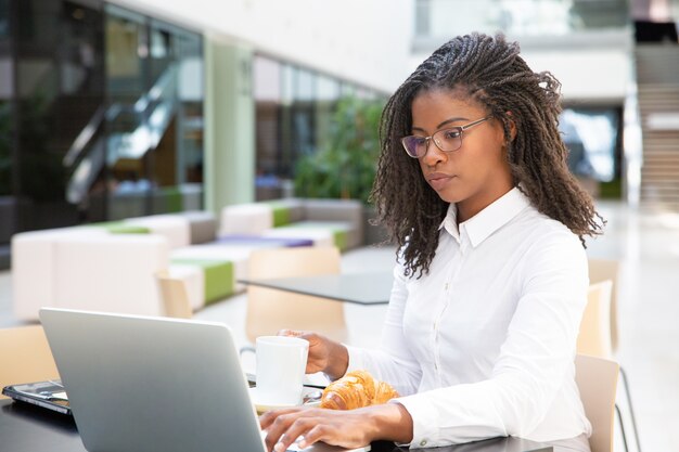 Serious young businesswoman having breakfast