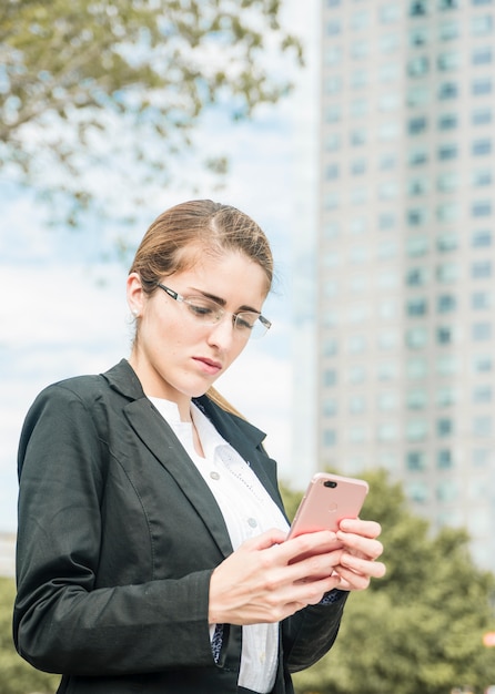 携帯電話を使用して眼鏡をかけている深刻な若い実業家