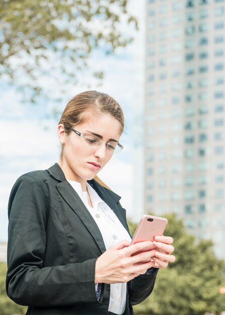 휴대 전화를 사용하여 안경을 쓰고 심각한 젊은 사업가