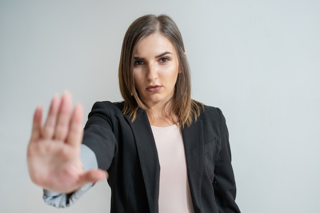 Serious young Caucasian businesswoman showing stop gesture