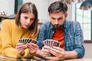 Free photo serious young couple looking at their cards playing the board game