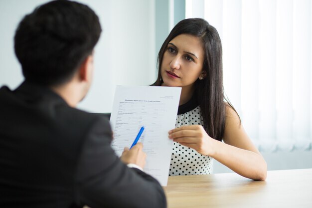Serious young female manager showing contract to partner