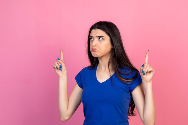 A serious young lady pointing her fingers up High quality photo