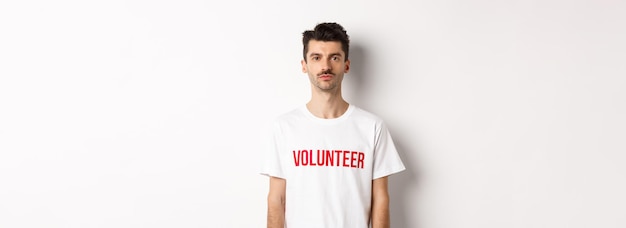 Serious young male volunteer in white tshirt looking at camera ready to help