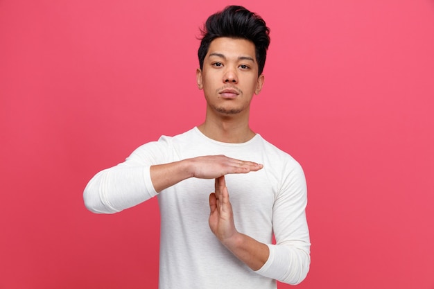 Serious young man doing timeout gesture 