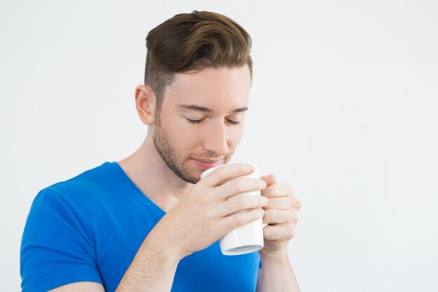 Serious young man drinking tasty coffee
