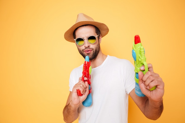 Free photo serious young man holding toy water guns