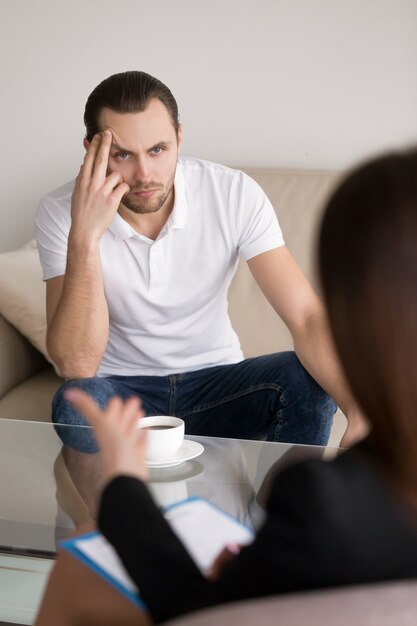 女性心理学者、顧問またはコンサルタントを聞いている深刻な若い男