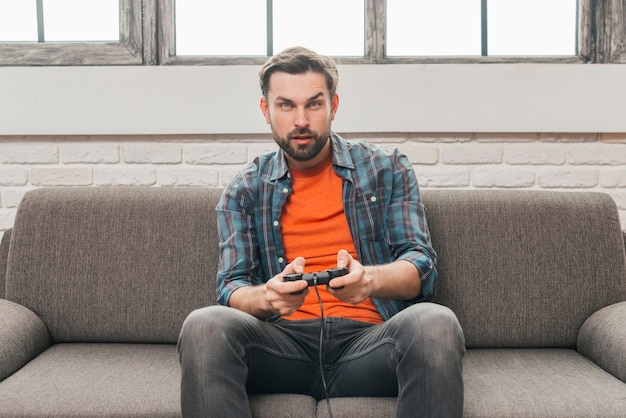 無料写真 ビデオゲームでソファーに座っていた深刻な若い男