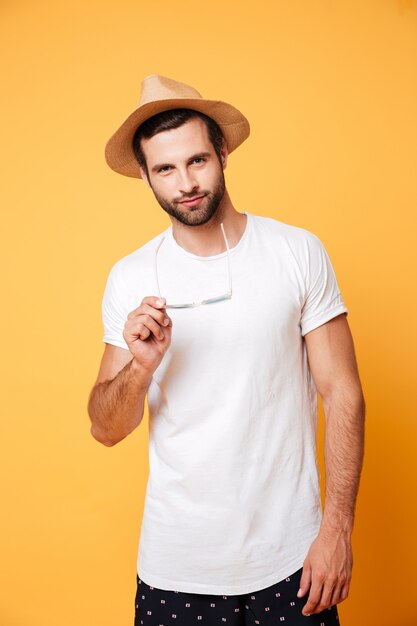 Serious young man standing isolated over yellow wall