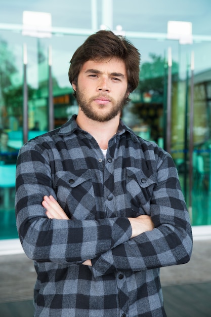 Free photo serious young man standing outdoors with his arms crossed