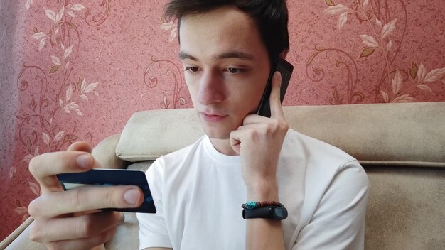 Serious young man talking on phone for online shopping