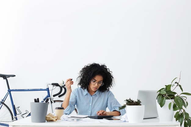 Free photo serious young mixed race female accountant working on financial report
