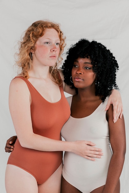 Serious young multi ethnic women standing together against grey background