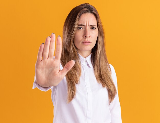 Serious young pretty caucasian girl gestures stop sign